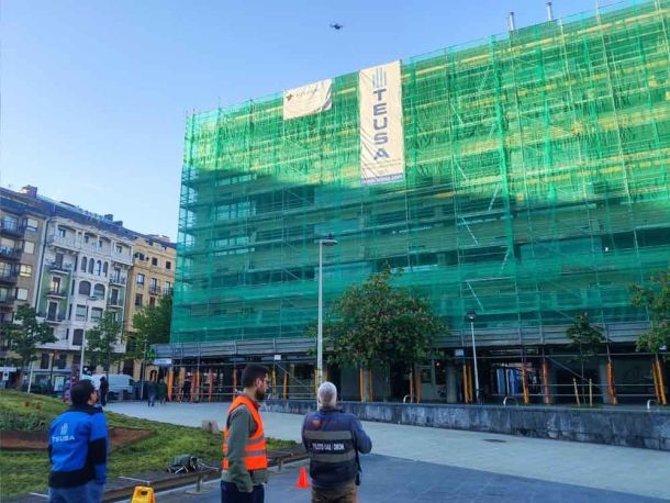 Pilotos de drones realizando inspección de fachada con andamios